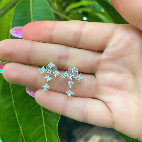 hand holding a pair of cross earrings