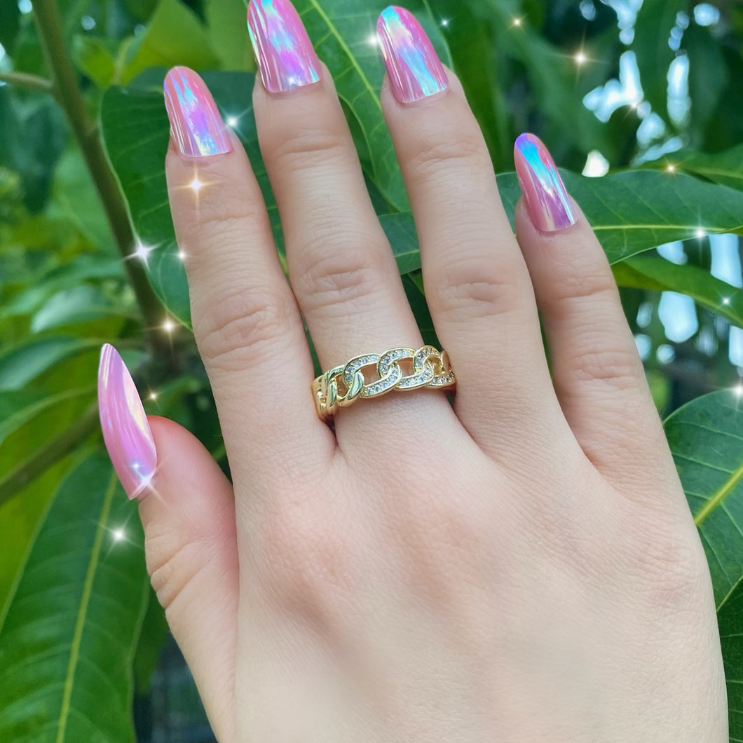 Hand with pink nails wearing a rhinestone cuban link ring.