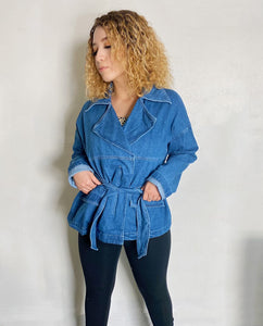 Girl with curly hair wearing a blue denim jacket.